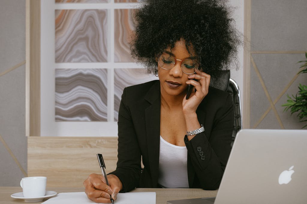 Businesswoman making a phone call while working at the desk, focused and professional.